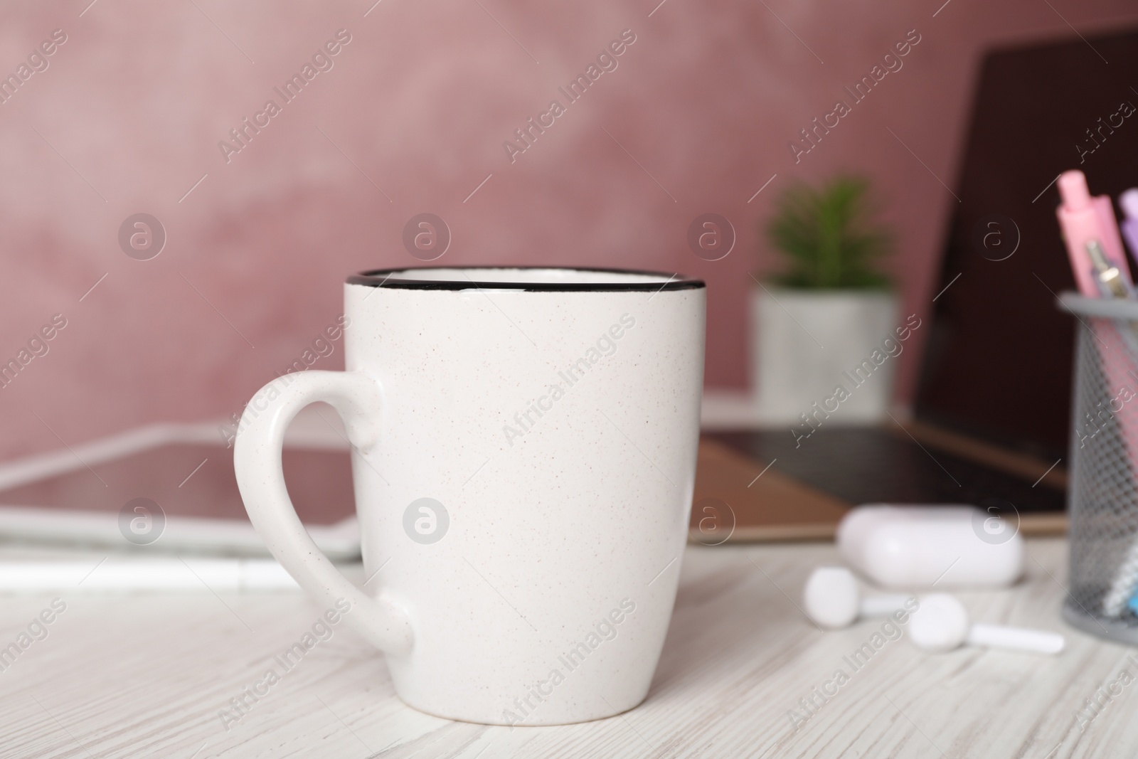 Photo of Coffee Break at workplace. Cup of hot drink on white wooden table