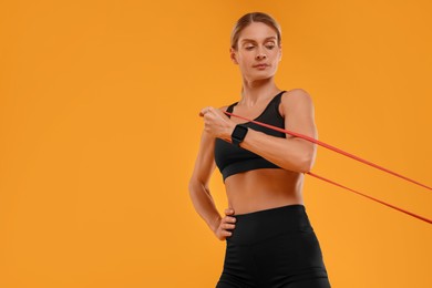Photo of Woman exercising with elastic resistance band on orange background, low angle view. Space for text