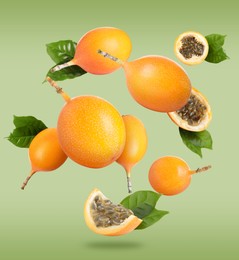 Delicious ripe granadillas with leaves falling on light green background