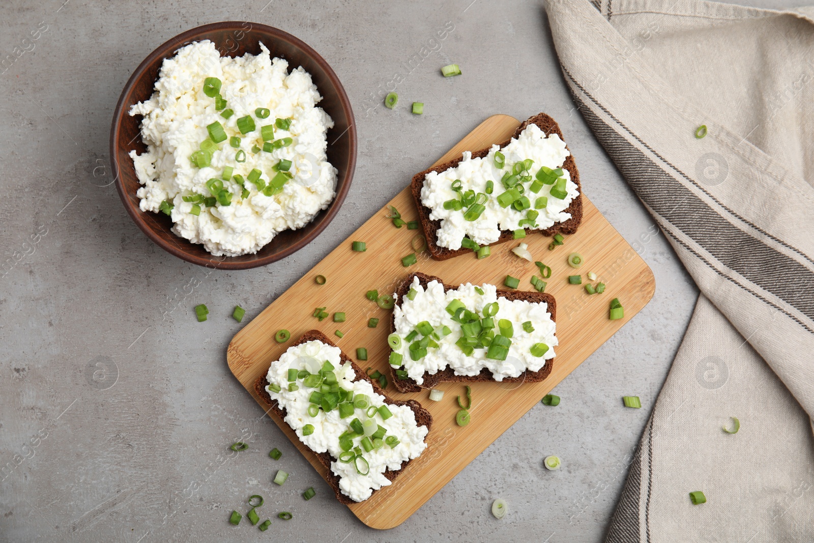 Photo of Bread with cottage cheese and green onion on light grey table, flat lay