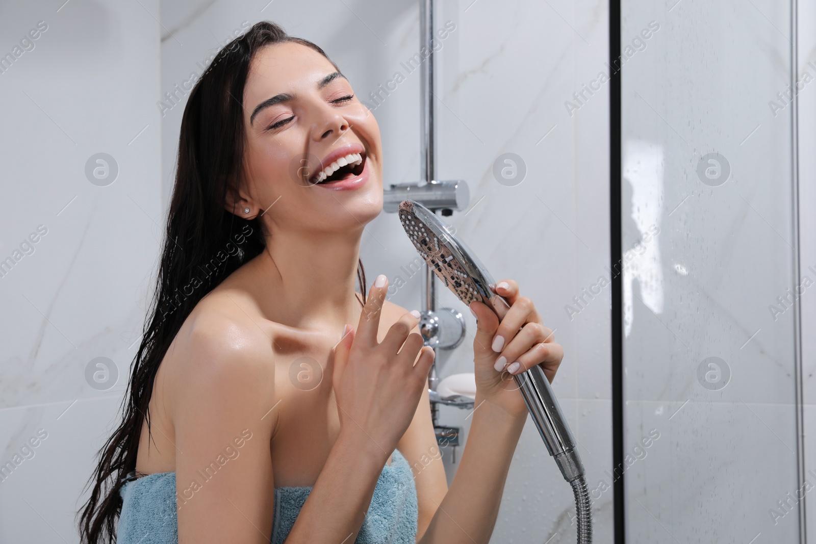 Photo of Beautiful young woman with towel singing while taking shower