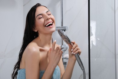 Photo of Beautiful young woman with towel singing while taking shower