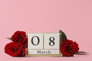 Photo of Wooden block calendar with date 8th of March and roses on pink background, space for text. International Women's Day