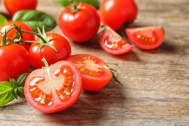 Photo of Fresh cherry tomatoes with basil on wooden background. Space for text