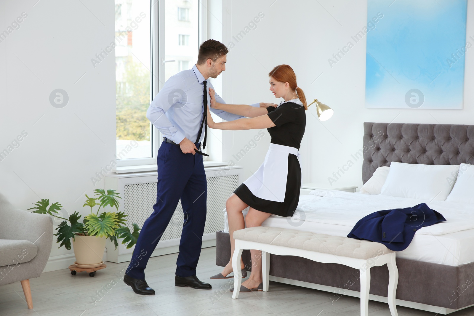 Photo of Man molesting chambermaid in bedroom. Sexual harassment at work