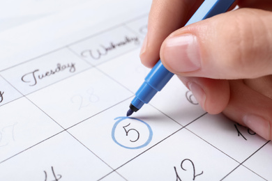 Woman marking date in calendar with felt pen, closeup