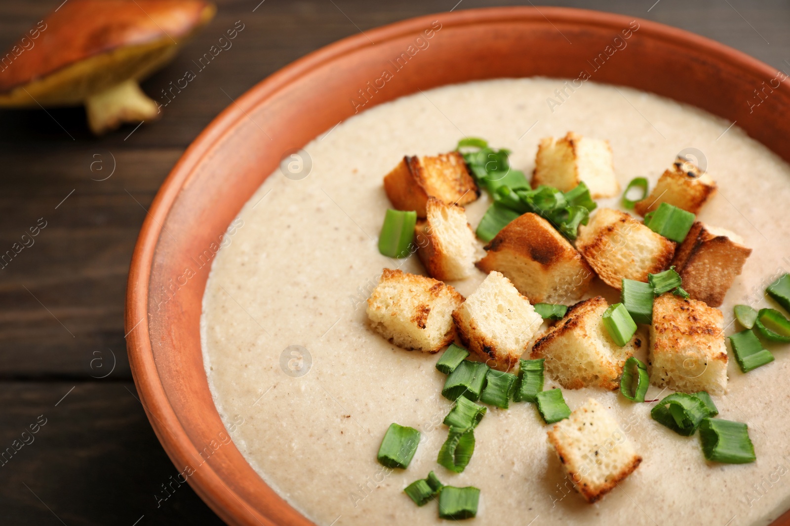 Photo of Bowl of fresh homemade mushroom soup on wooden table, closeup