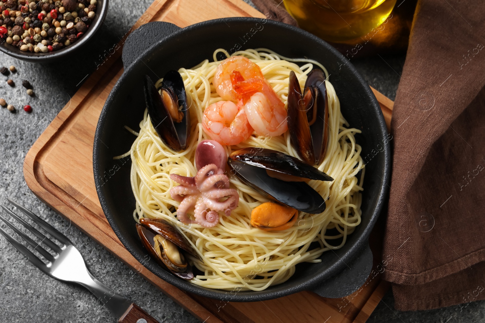 Photo of Delicious pasta with sea food served on grey table, flat lay