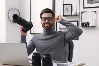 Photo of Professional photographer in glasses with digital camera at table in office