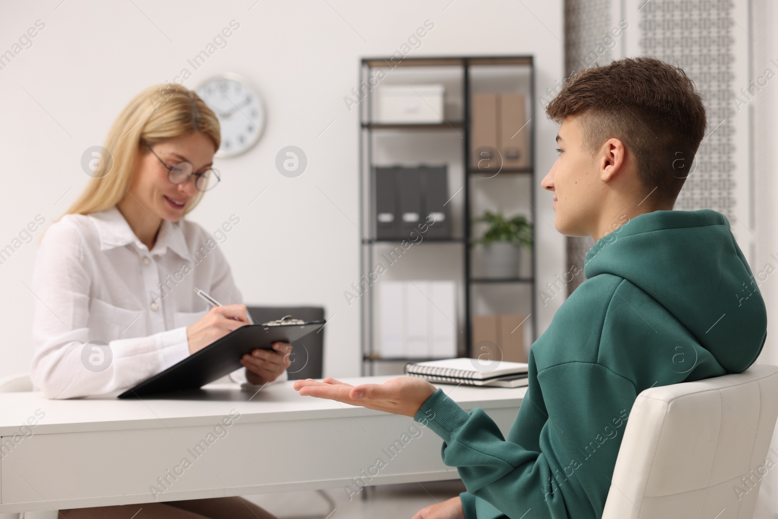 Photo of Psychologist working with teenage boy at table in office