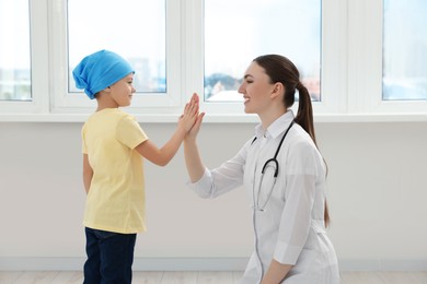 Childhood cancer. Doctor and little patient giving high five in hospital