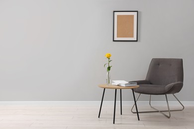 Photo of Comfortable armchair and coffee table near light grey wall indoors, space for text. Interior design
