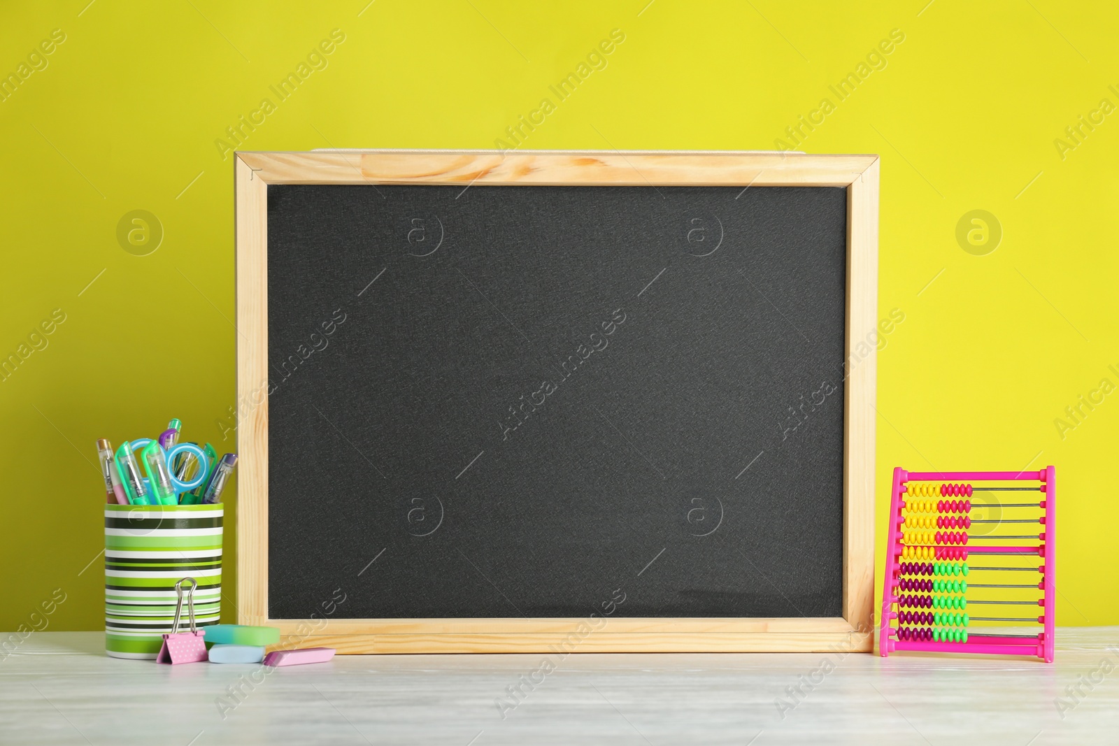 Photo of Small chalkboard and different school stationery on table