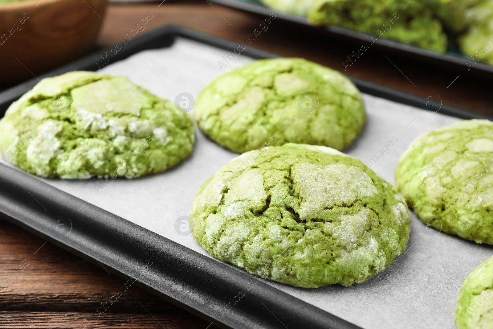 Photo of Baking tray with tasty matcha cookies on wooden table, closeup