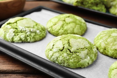 Baking tray with tasty matcha cookies on wooden table, closeup