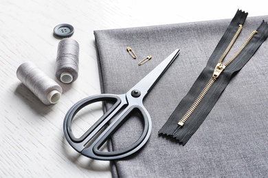 Photo of Set of tailoring accessories and fabric on light background