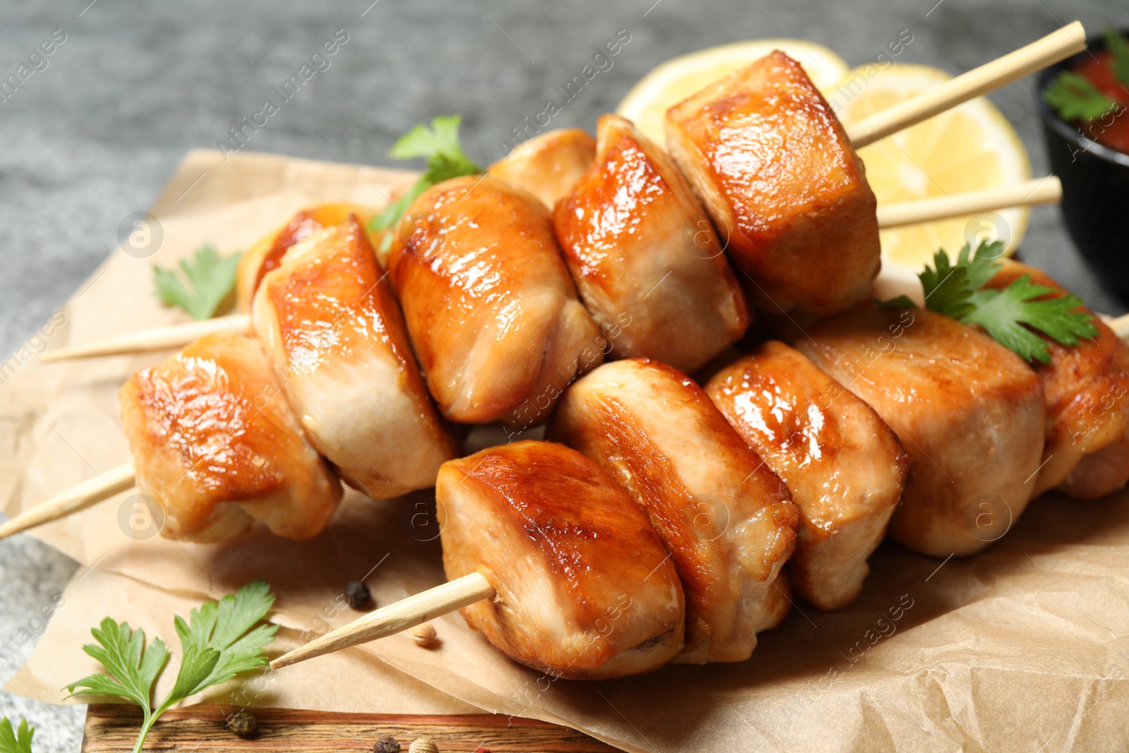 Photo of Delicious chicken shish kebabs with parsley on grey background, closeup