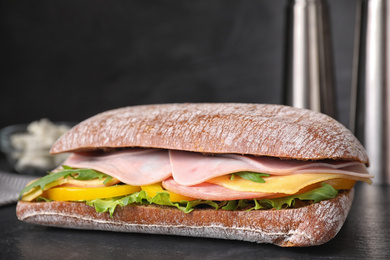 Photo of Tasty sandwich with ham on black table, closeup