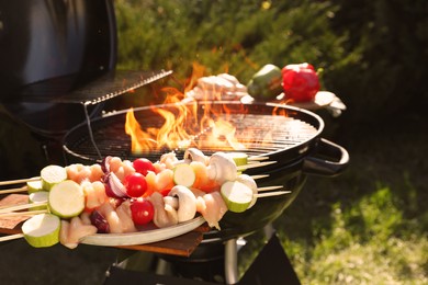 Photo of Skewers with meat and vegetables near barbecue grill outdoors