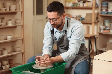 Man crafting with clay on potter's wheel in workshop