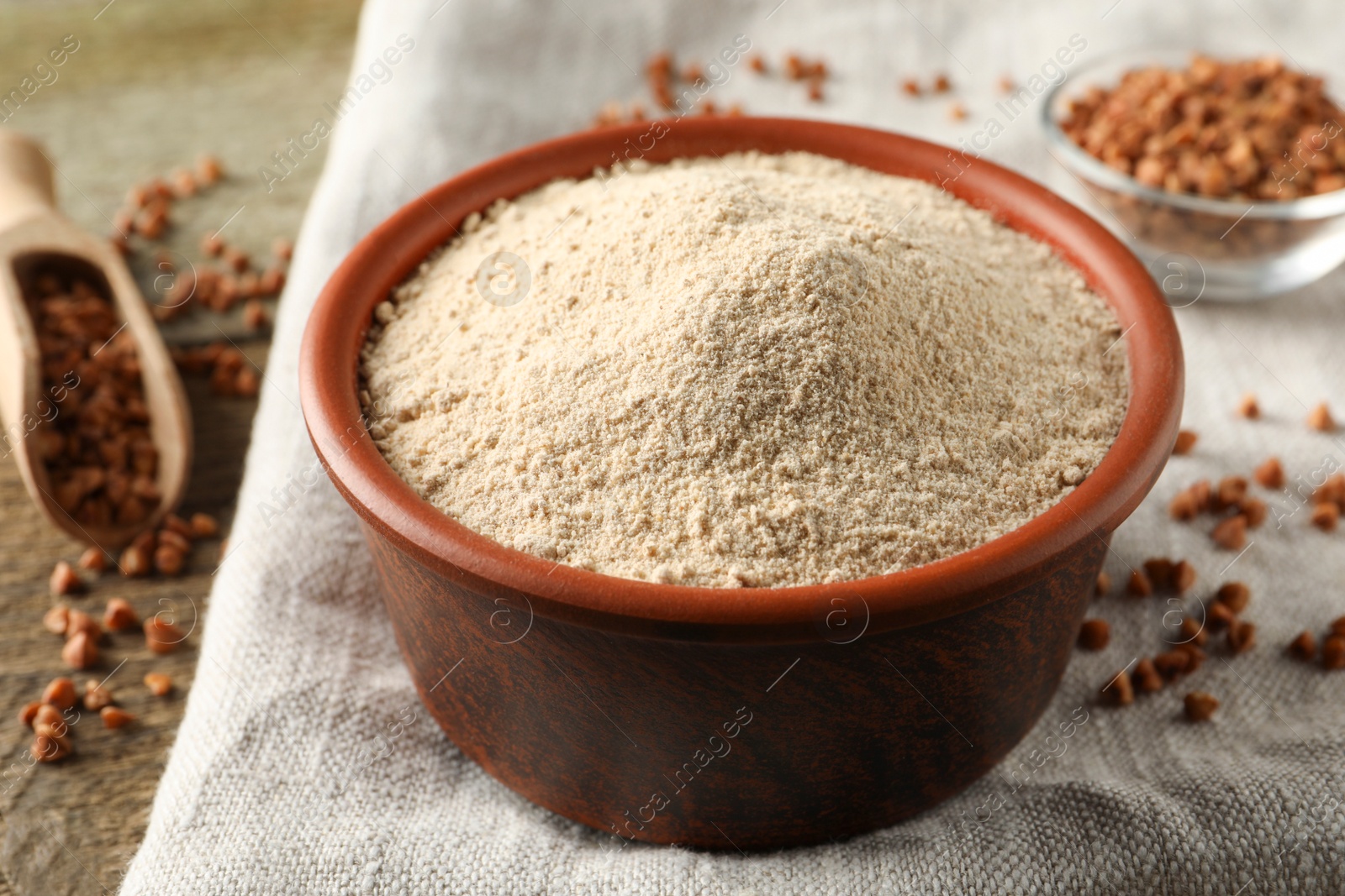 Photo of Bowl of buckwheat flour and cloth on wooden table