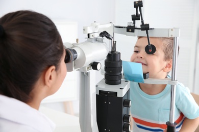 Children's doctor examining little boy with ophthalmic equipment in clinic