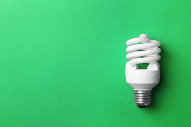 Photo of New fluorescent lamp bulb on green background, top view. Space for text