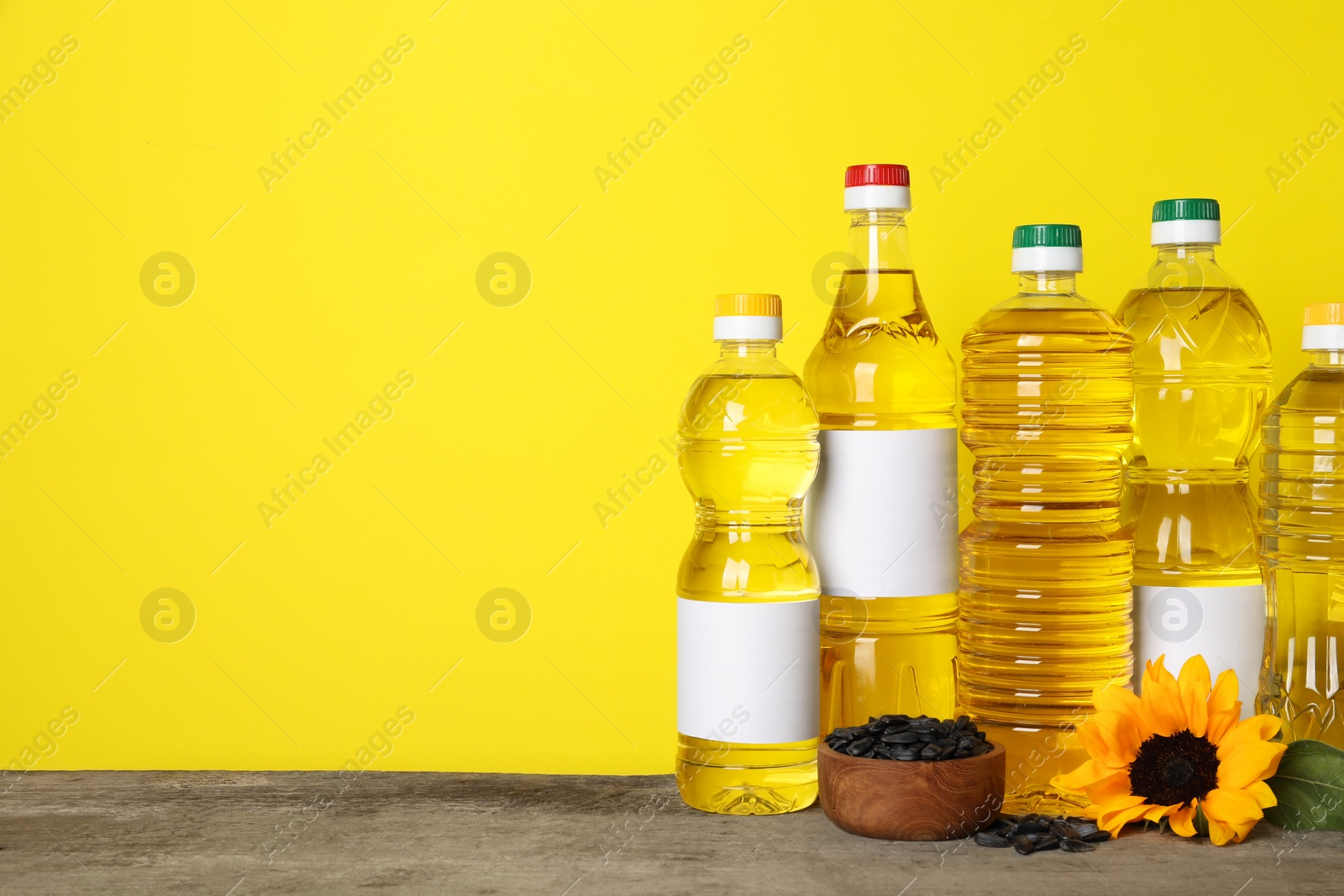 Photo of Bottles of cooking oil, sunflower and seeds on wooden table, space for text