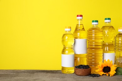 Bottles of cooking oil, sunflower and seeds on wooden table, space for text