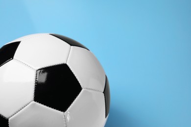 Photo of One soccer ball on light blue background, space for text. Sports equipment
