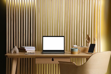 Photo of Stylish workplace with laptop and stationery on wooden table indoors