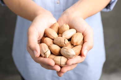 Photo of Woman holding pecan nuts in hands, closeup