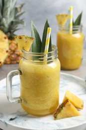 Photo of Tasty pineapple smoothie and sliced fruit on table