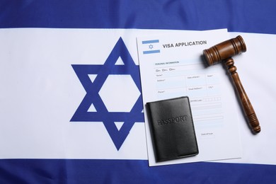 Immigration to Israel. Visa application form, gavel and passport on flag, flat lay. Space for text