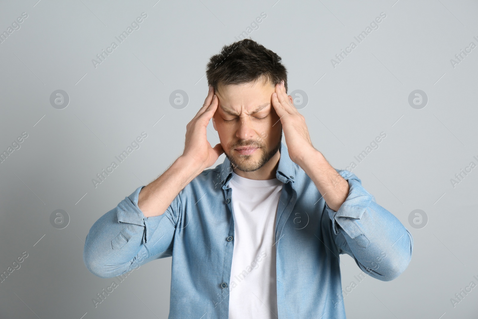 Photo of Man suffering from terrible migraine on light grey background