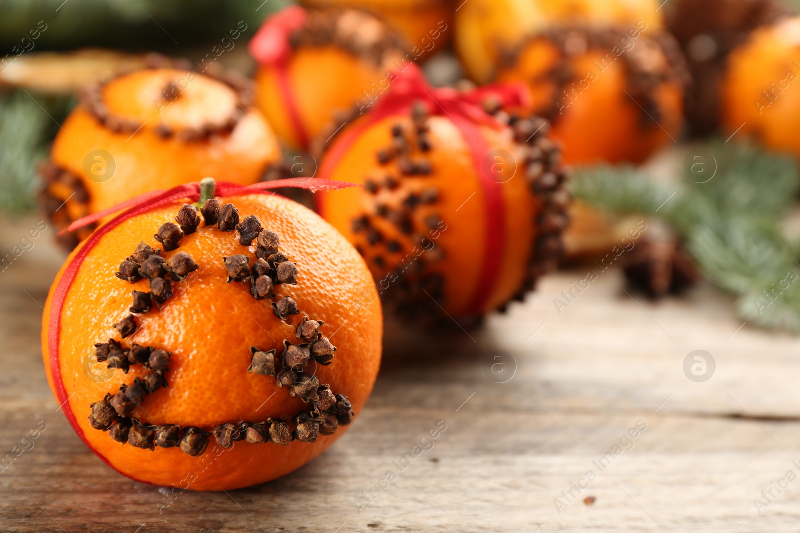 Photo of Pomander balls made of fresh tangerines with cloves  on wooden table, closeup. Space for text