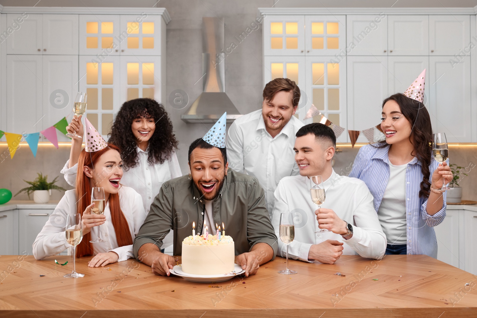 Photo of Happy friends with tasty cake celebrating birthday in kitchen