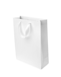 Paper shopping bag with ribbon handles on white background. Mockup for design