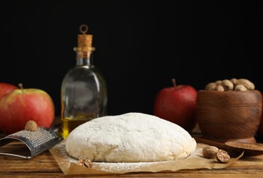 Photo of Raw dough, nutmeg seeds and other ingredients for pastry on wooden table