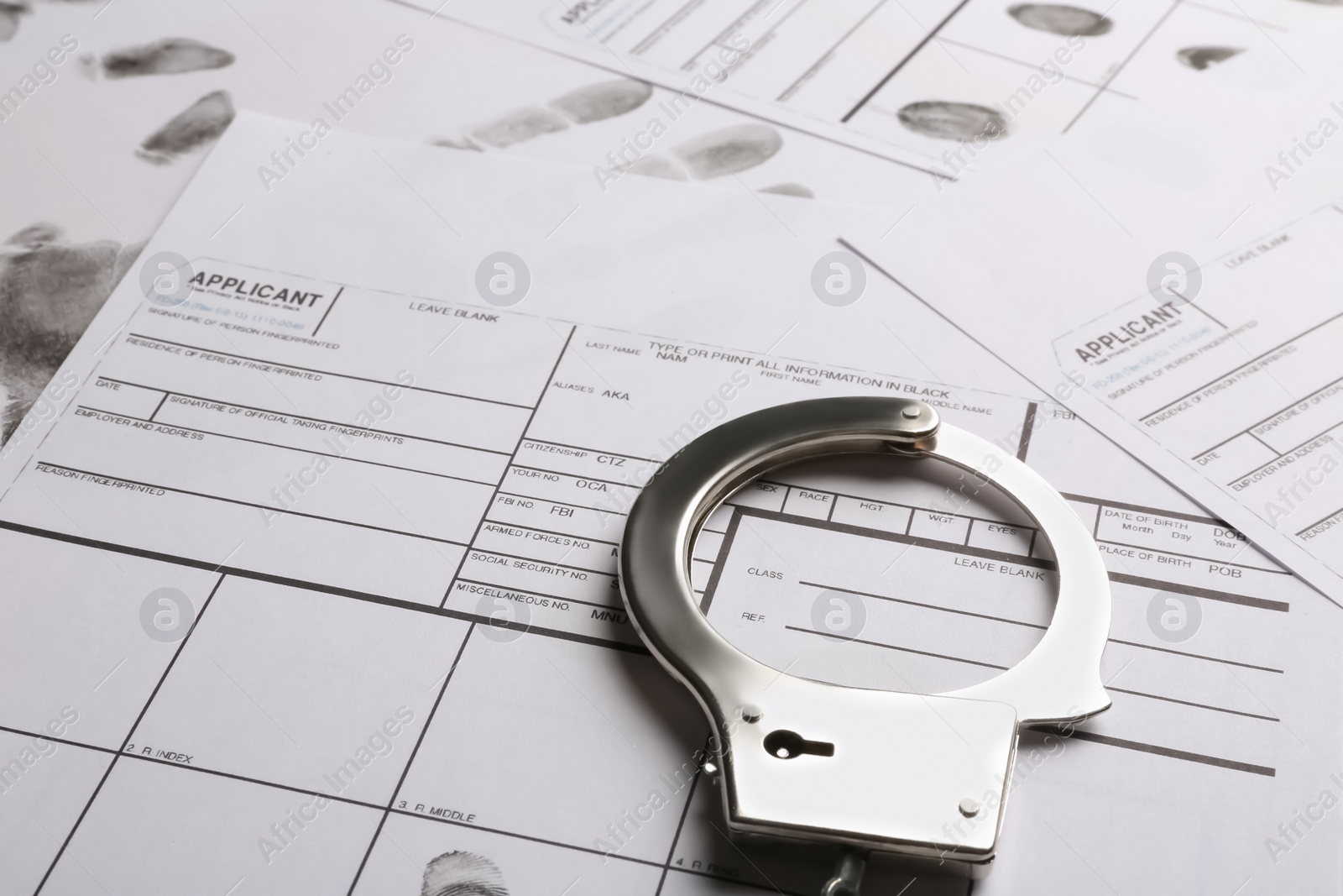 Photo of Handcuffs and fingerprint record sheets, closeup. Criminal investigation