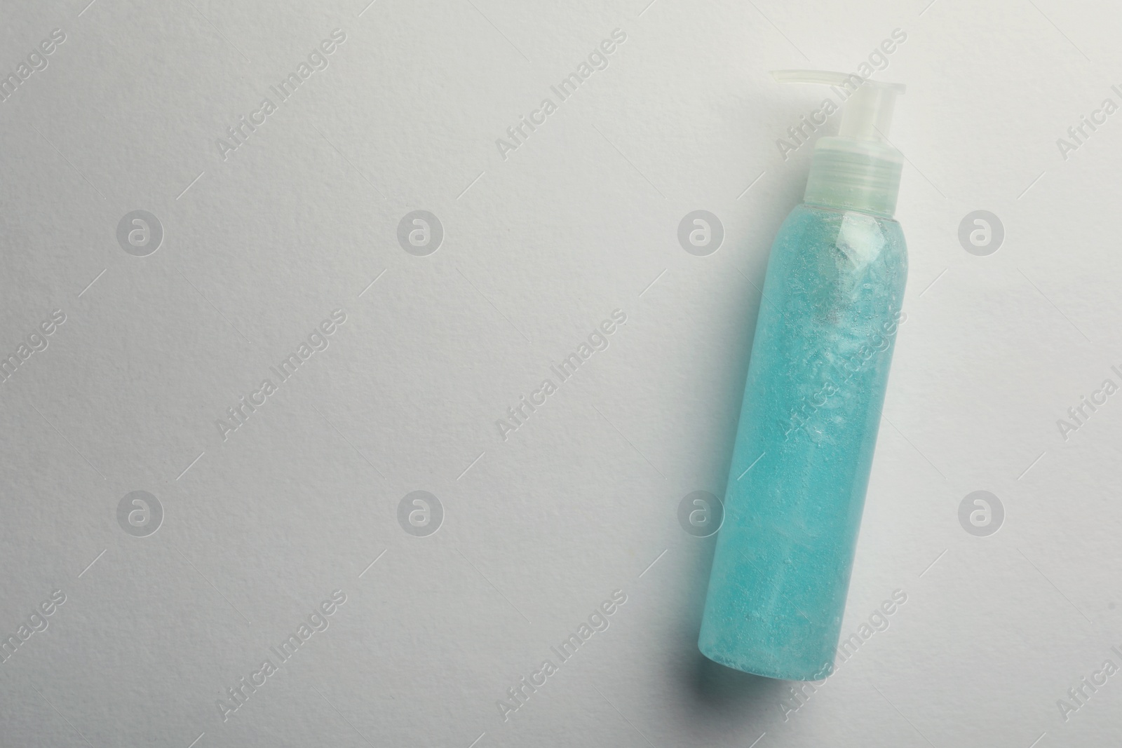 Photo of Bottle of blue cosmetic gel on light background, top view. Space for text