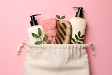 Photo of Preparation for spa. Compact toiletry bag with different cosmetic products and twigs on pink background, flat lay