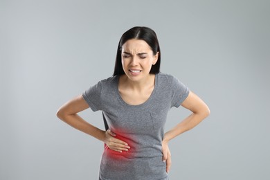 Woman suffering from liver pain on grey background