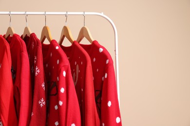 Photo of Rack with different Christmas sweaters on beige background, space for text
