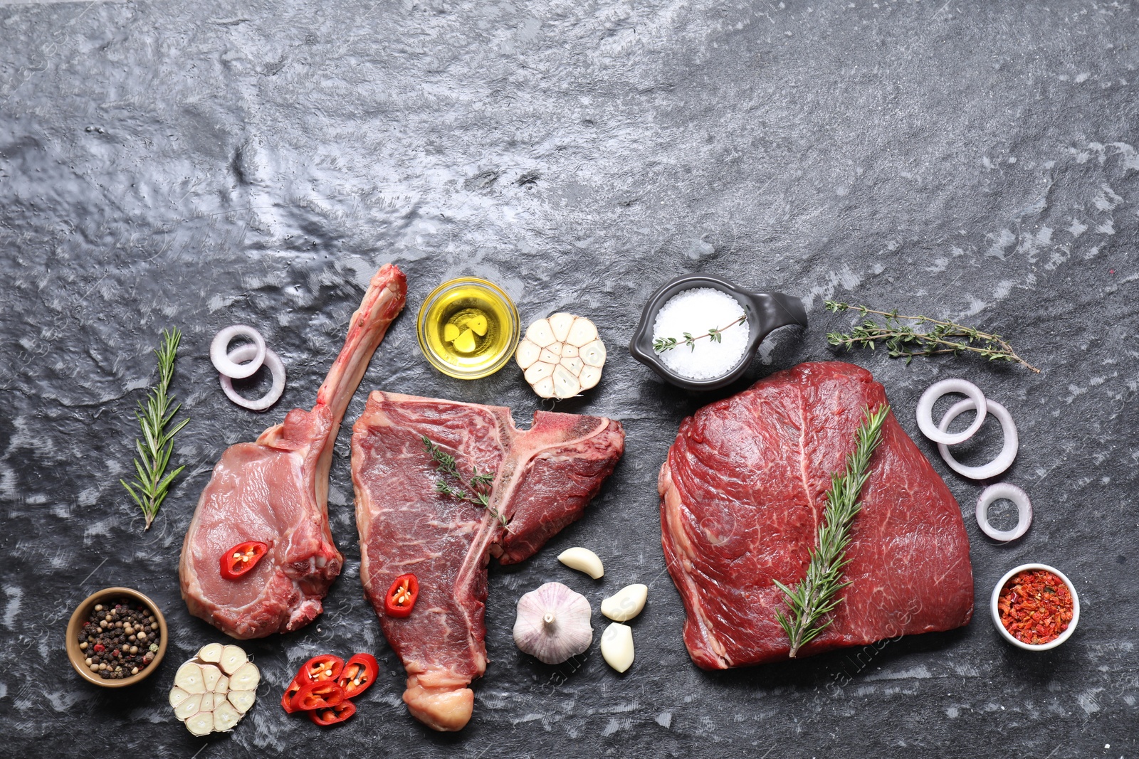 Photo of Fresh raw beef cuts and different spices on grey textured table, flat lay. Space for text