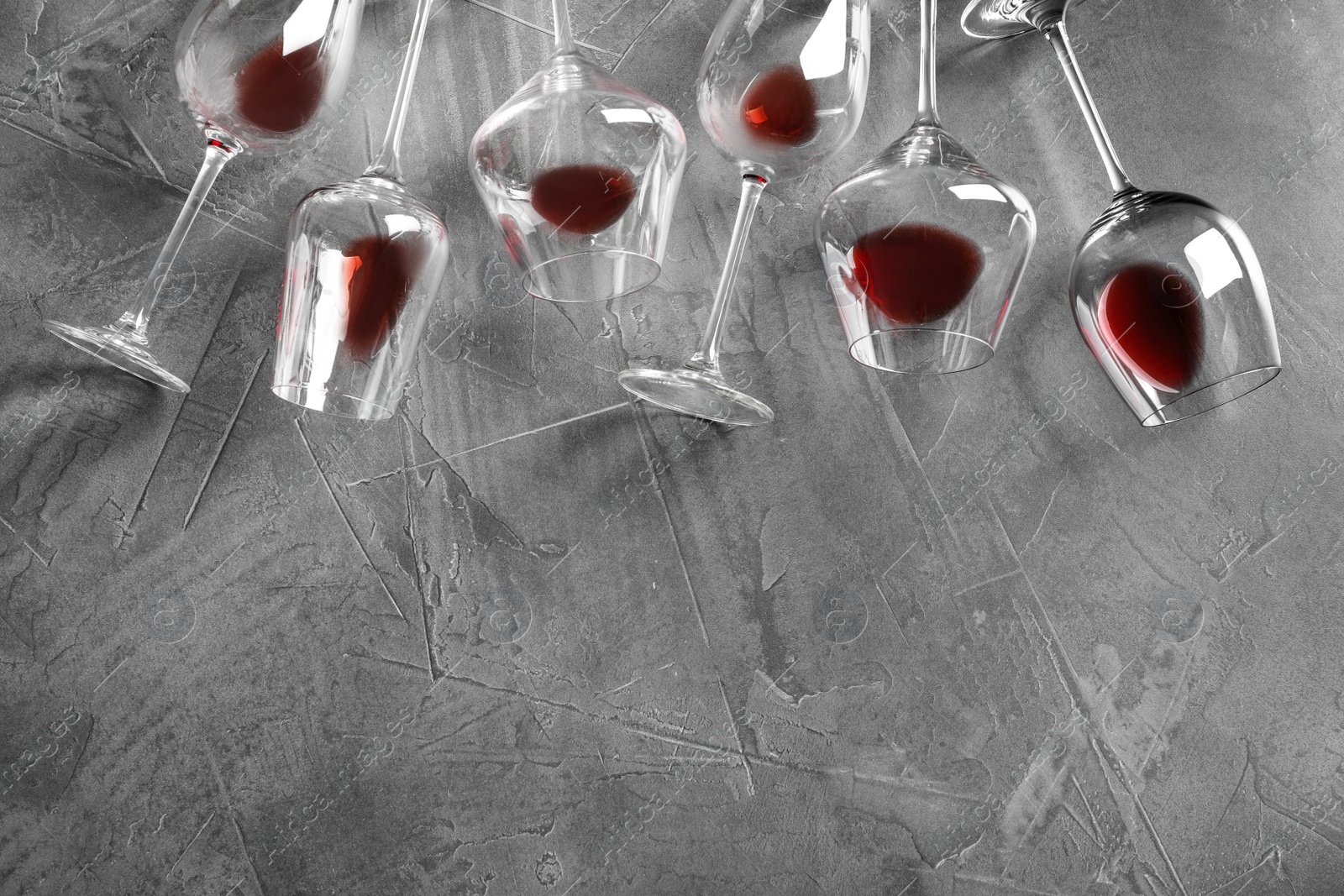 Photo of Different glasses with red wine on grey background, flat lay. Space for text