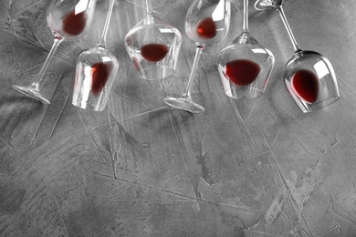 Different glasses with red wine on grey background, flat lay. Space for text