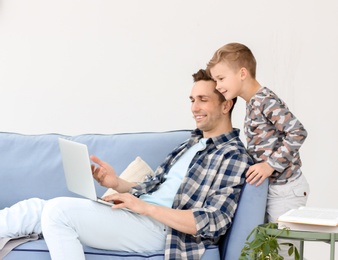 Photo of Dad and his son with laptop at home