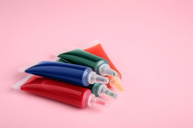 Photo of Tubes with different food coloring on pink background, space for text