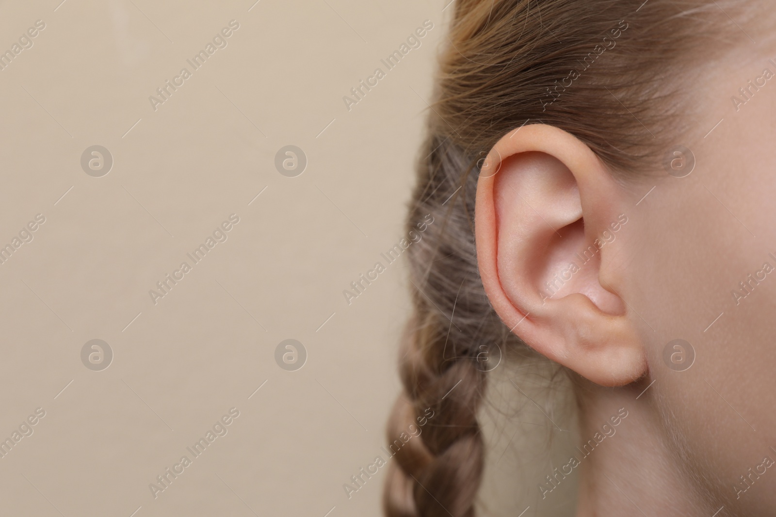 Photo of Cute little girl on beige background, closeup of ear. Space for text